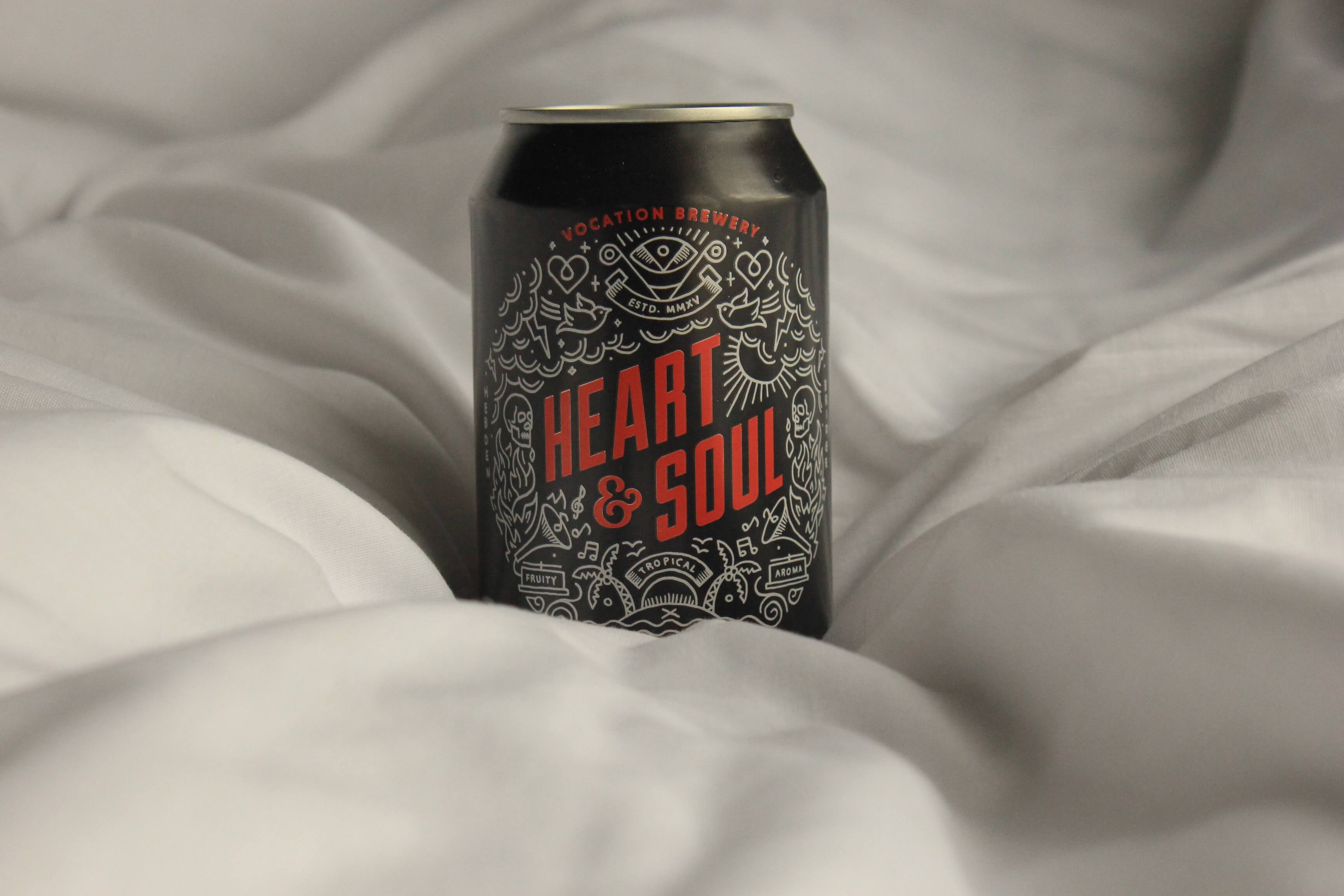 Photograph of a can of soda with the brand name Heart & Soul. The can is black, the logo and writing is red with white illustrations.
