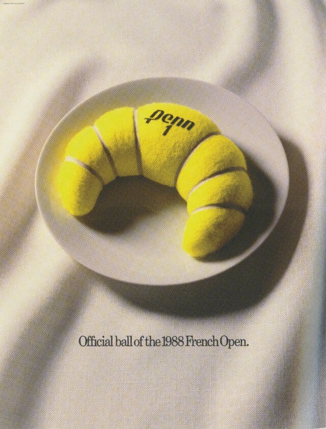 Yellow tennis ball on a white plate. The tennis ball is shaped like a croissant.
