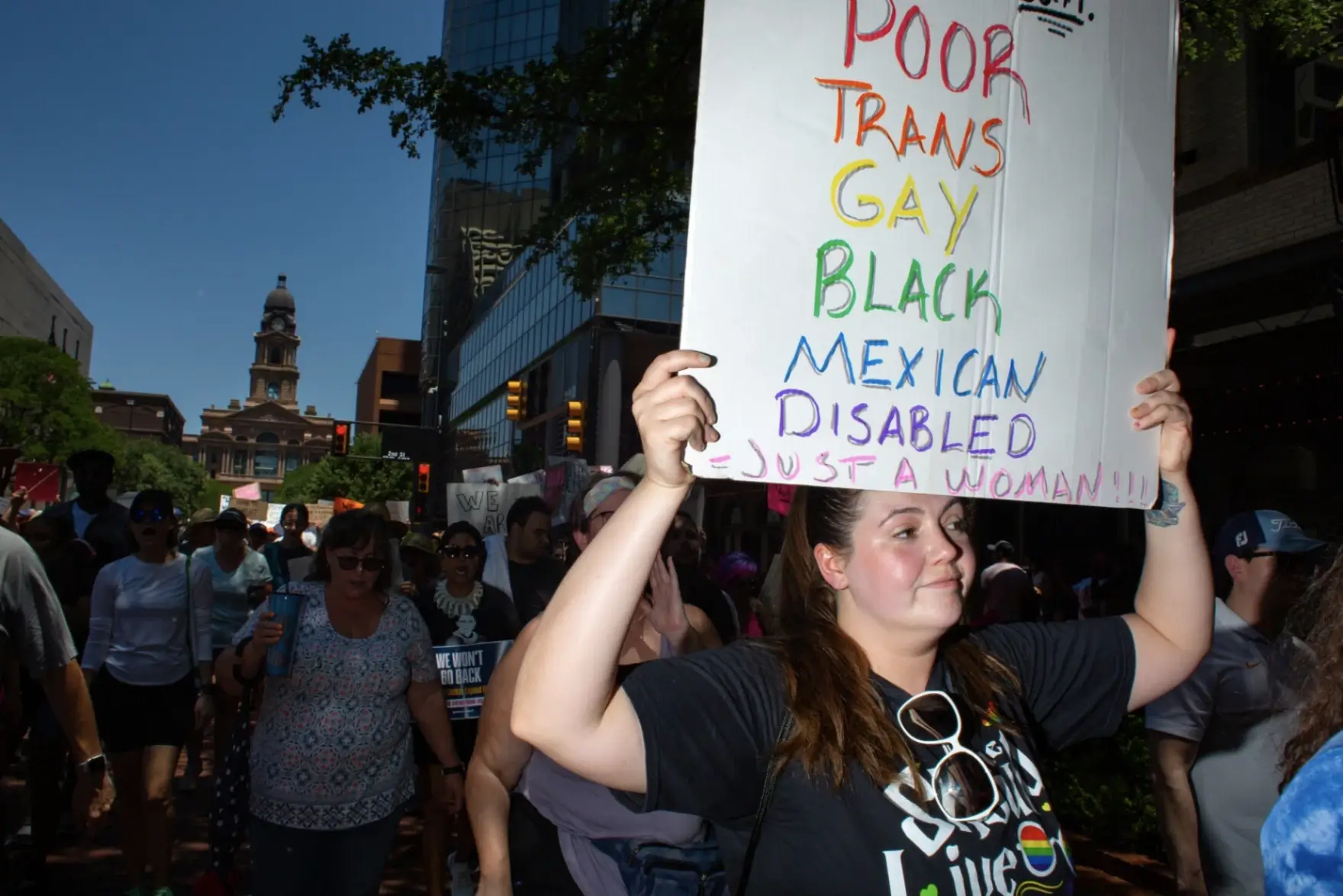 Group of women on a protest holding banners of equality including Poor, Trans, Gay, Black, Mexican, Disabled.
