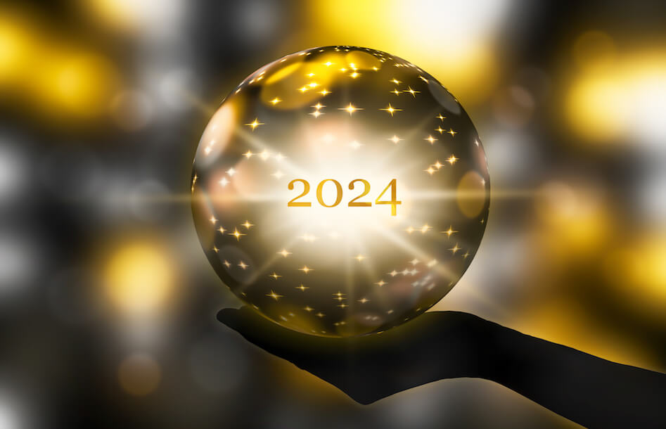 Silhouette einer Hand mit einer Kristallkugel in der Hand, auf der das Jahr 2024 in Gold eingeprägt ist.