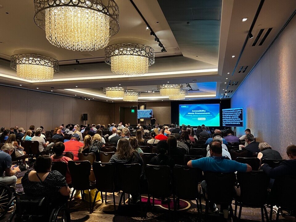 A picture of a panel at the Disability:IN Conference. In the front of the room is a panel of speakers sitting at a table with an ASL interpreter.